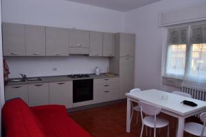 デルヴィオにあるCasa di Leoの白いキャビネット、テーブル、赤いソファ付きのキッチンが備わります。