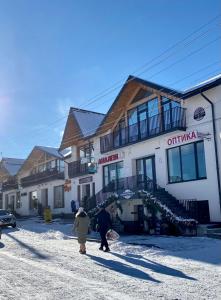 two people walking in the snow in front of a building at Апартаменти Пасаж in Skhidnitsa