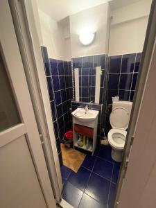 a blue tiled bathroom with a toilet and a sink at Garsoniera in Bacău