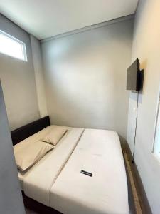 a small bedroom with a white bed and a television at Sentul Inn in Citaringgul 1