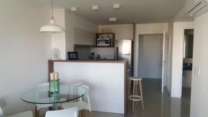 a kitchen with a glass table and some stools at Apartamento Chronos in Punta del Este