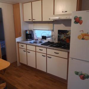a kitchen with white cabinets and a sink and a refrigerator at Bungalow a Hyeres prévoir serviettes de toilette et linge de lits in Hyères +1 photo