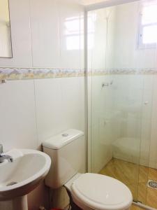 a white bathroom with a toilet and a sink at Moradas da Bibi in Guarda do Embaú