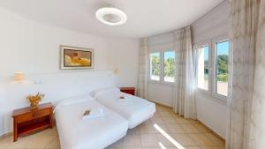 a white bedroom with a bed and a window at Greenview Villa by ON Travel in Oliva +59 photos