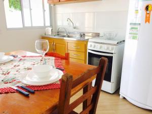 uma cozinha com uma mesa de madeira e um frigorífico branco em Moradas da Bibi em Guarda do Embaú