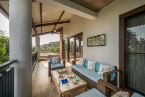 a living room with a couch and a table on a balcony at SaffronStays Casa Amore in Mahabaleshwar