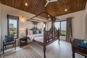 a bedroom with a canopy bed and a desk and window at SaffronStays Casa Amore in Mahabaleshwar +42 photos