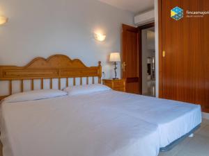 a bedroom with a large white bed with a wooden headboard at Apartamento Rosa in Cala Bona +15 photos