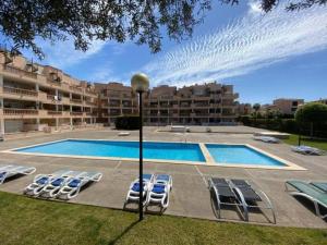 a swimming pool with lounge chairs in front of a building at Apartamento Rosa in Cala Bona