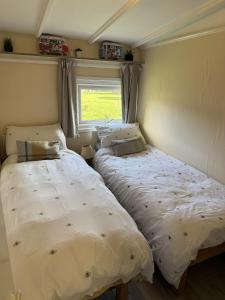 two beds in a small room with a window at Lodge 51 - Caer Beris Park - No Tradesmen in Maesmynis