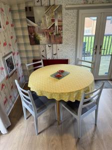a dining room table with a yellow table and chairs at Lodge 51 - Caer Beris Park - No Tradesmen in Maesmynis +6 photos