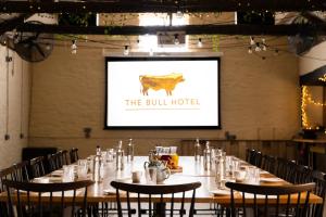 a long table with chairs in a room with a screen at The Bull Hotel in Bridport