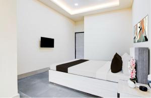 a white bedroom with a bed and a tv at Townhouse Oak Howrah Junction Kolkata in Kolkata