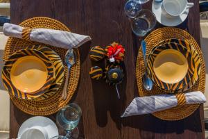 a wooden table with yellow and black striped plates and cups at Ikhaya Safari Lodge in Cape Town