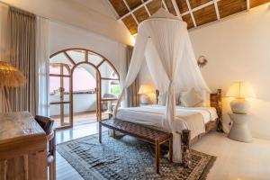 a bedroom with a bed with a canopy at Mowies On The Beach in Gili Islands +84 photos