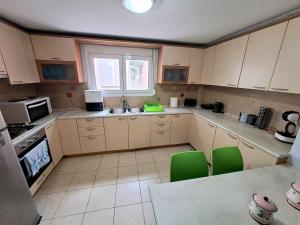 a kitchen with white cabinets and green chairs at Home4you in Skala Mistegnon