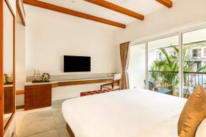 a bedroom with a bed and a tv and a balcony at Mango Hill Hotel Velankanni in Velankanni +6 photos
