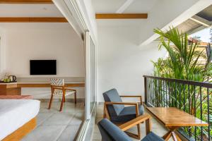 a room with a balcony with a tv and a table and chairs at Mango Hill Hotel Velankanni in Velankanni