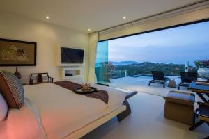 a bedroom with a bed and a large glass window at Villa Danisa 4BR Panoramic Ocean View with Infinity Pool & Private Gym in Choeng Mon Beach