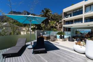 a patio with two chairs and a blue umbrella at Azamare Guest House in Cape Town