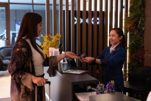 a woman is handing a man a cell phone at Grand Kingsgate Jaddaf Waterfront Hotel by Millennium in Dubai
