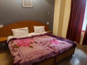 a bed with a pink comforter with roses on it at Hotel Shree Ram in Shimla