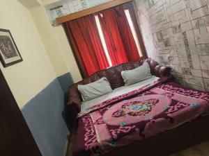 a couch with a blanket on it in front of a window at Hotel Shree Ram in Shimla