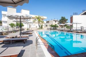 a swimming pool with benches and umbrellas at a hotel at Olevia Comfort in Faliraki