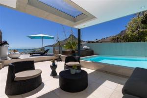 a patio with a swimming pool and chairs and a swimming pool at Azamare Guest House in Cape Town