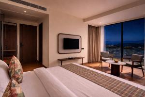 a hotel room with a bed and a large window at Avisa Hotel & Resort Abu Road - Luxury Pool & Mountain View in Ābu Road