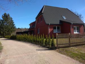 a red house with a fence and christmas trees at Ferienhäuser Eggers in Bispingen