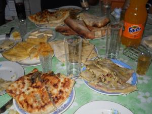 a table topped with plates of pizza and bread at Lagami house in Mestia