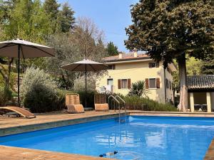 a swimming pool with two umbrellas and a house at Relais Villa Alma in Castion Veronese