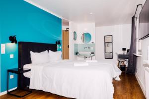 ein Schlafzimmer mit einem weißen Bett und einer blauen Wand in der Unterkunft Hotel Palmenbad in Kassel