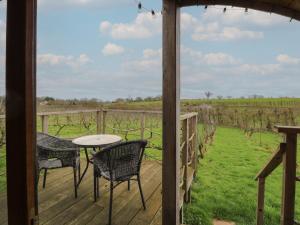 a porch with a table and chairs and a view of a vineyard at Grape Escape in Halesworth
