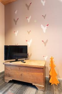 a living room with a tv and birds on the wall at Casa Monet 41 in Saint Vincent