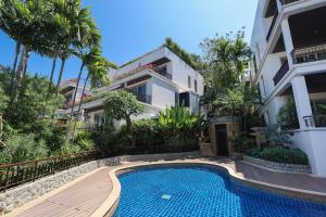 a villa with a swimming pool in front of a building at Kata gardens luxury 2bedroom 4B Near Kata Noi Beach in Kata Beach