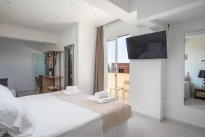 a white bedroom with a bed and a flat screen tv at Olevia Comfort in Faliraki