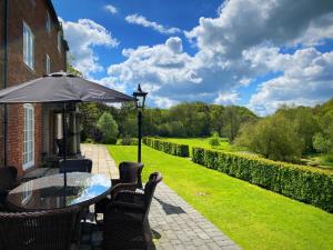 a glass table with an umbrella on a patio at Bettws Hall Accommodation in Newtown