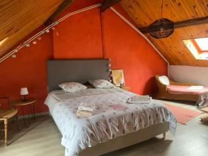 a bedroom with a bed with an orange wall at Le Caillou in Reuilly