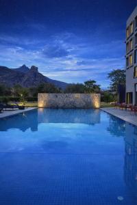 a hotel swimming pool at night with mountains in the background at Avisa Hotel & Resort Abu Road - Luxury Pool & Mountain View in Ābu Road