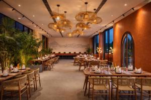 a restaurant with tables and chairs and chandeliers at Avisa Hotel & Resort Abu Road - Luxury Pool & Mountain View in Ābu Road