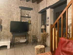 a living room with a television on a stone wall at Le Caillou in Reuilly