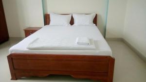 a bed with a wooden frame and white sheets at Homestay846 in Vung Tau