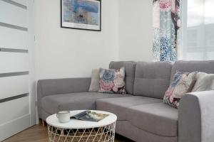 a living room with a couch and a coffee table at Sunset Resort Jasny Apartament z 1 Sypialnią 500 m od Plaży, Balkon & Parking by Noclegi Renters in Grzybowo