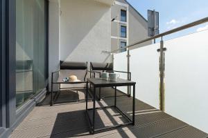 a balcony with two chairs and a table on it at Sunset Resort Jasny Apartament z 1 Sypialnią 500 m od Plaży, Balkon & Parking by Noclegi Renters in Grzybowo