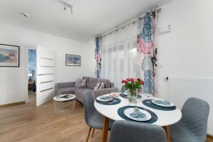 a living room with a white table and chairs at Sunset Resort Jasny Apartament z 1 Sypialnią 500 m od Plaży, Balkon & Parking by Noclegi Renters in Grzybowo