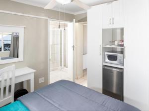 a white kitchen with a bed and a microwave at Mount Currie Inn in Kokstad