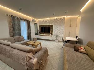 a living room with a couch and a table and a tv at Vila Floban & MIRDAR KOSHI in Sarandë
