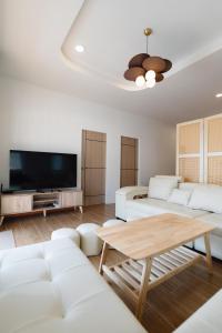 a living room with white furniture and a flat screen tv at Tenki poolvilla srisaket in Ban Phia Nam